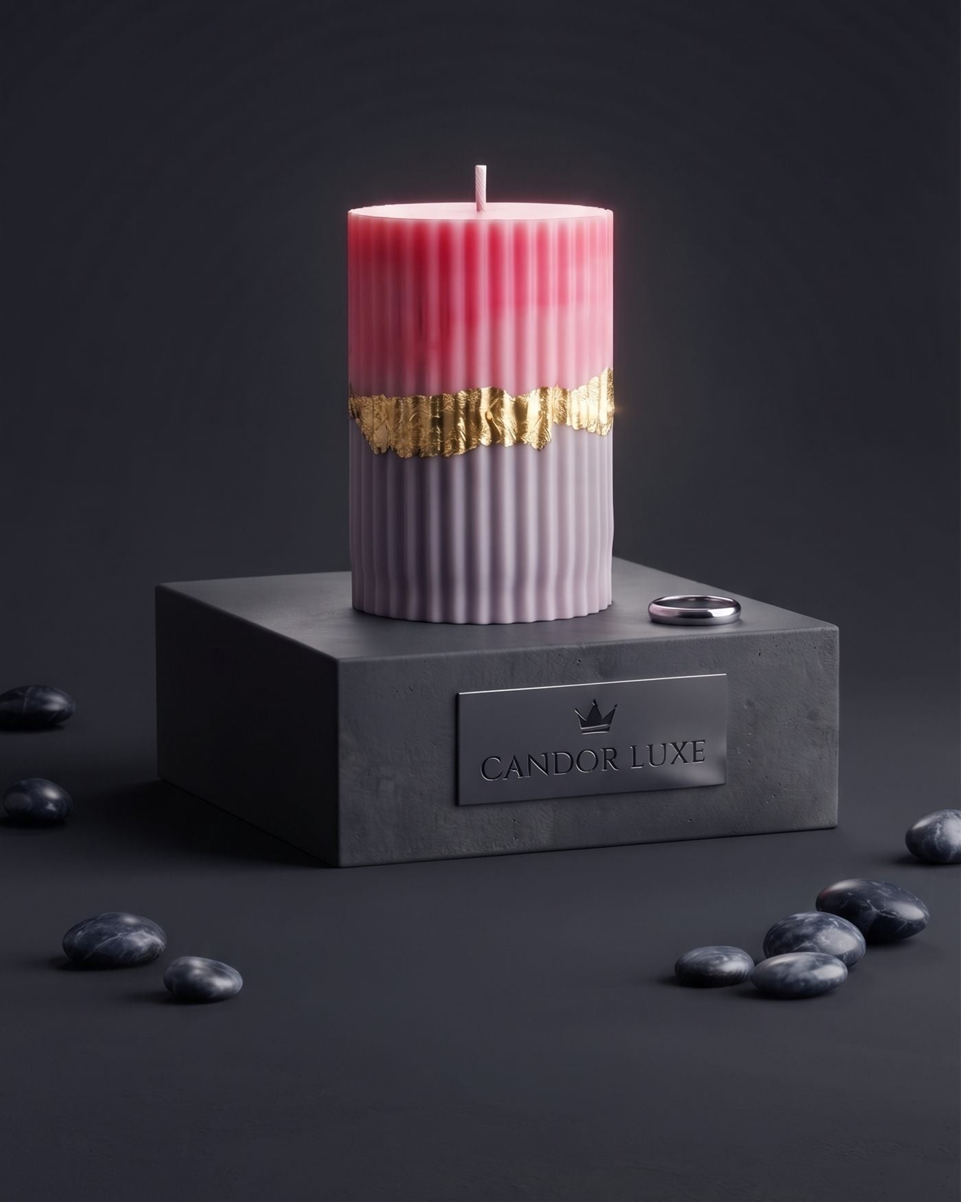 Gilded Ember, a rose and grey fluted pillar candle with a band of gold leaf, on a black plinth